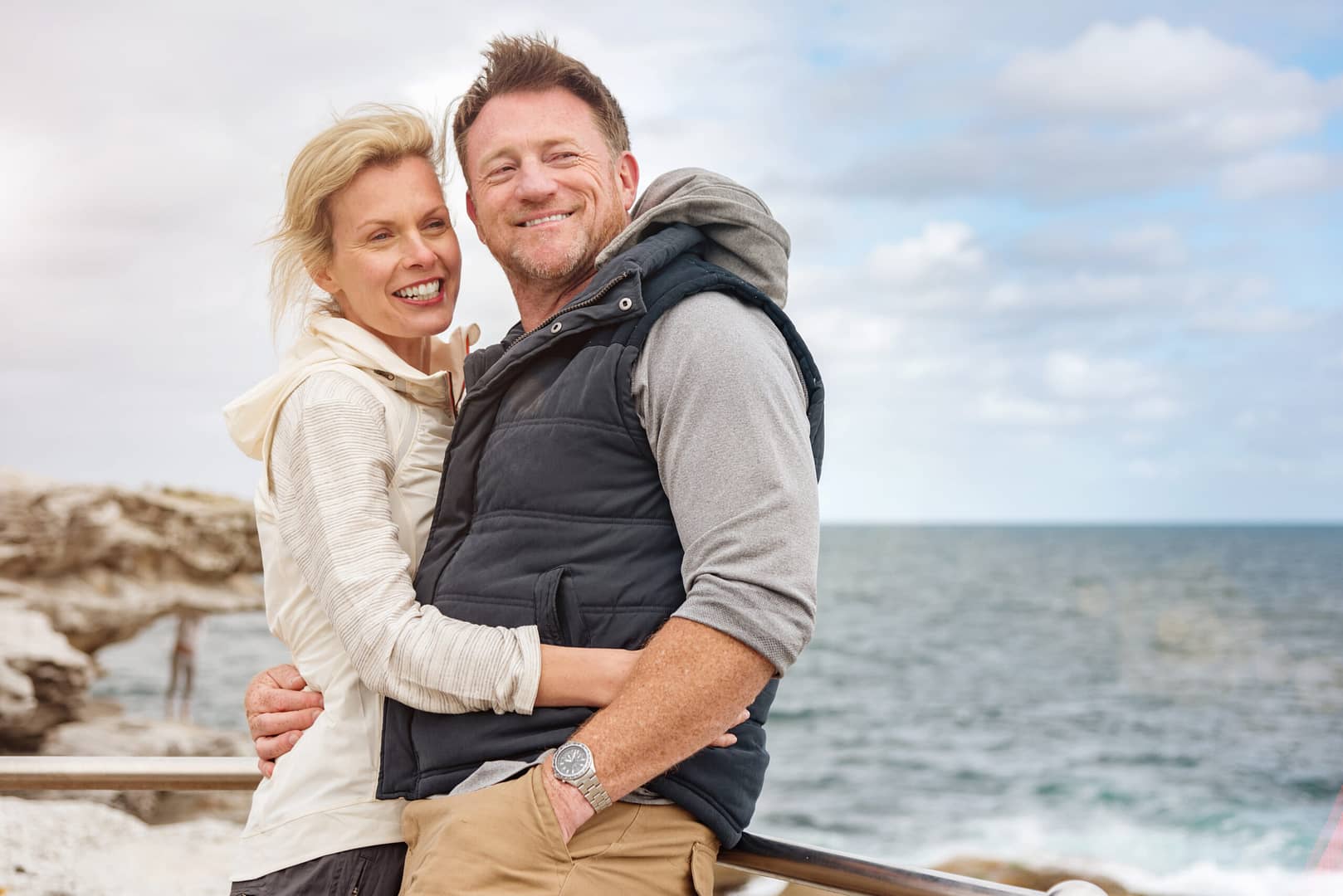 Happy middle aged couple holding each other by the sea